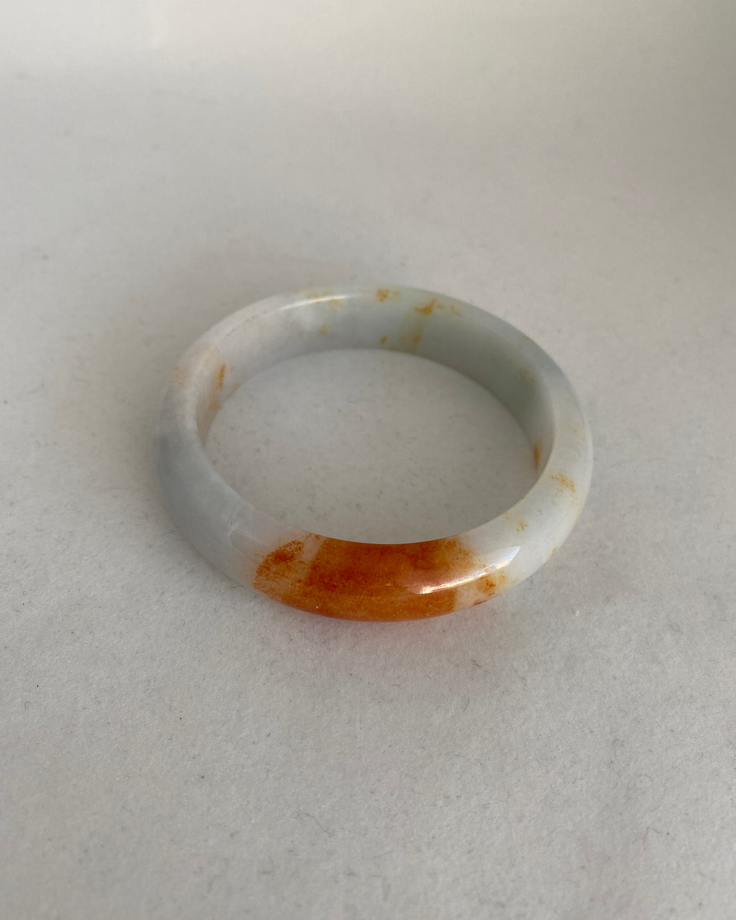 WHITE JADEITE JADE BANGLE WITH A BRIGHT ORANGE RED ( KOI). 57.5MM.